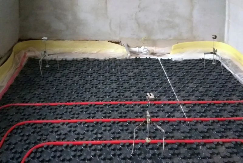 Okruhy podlahového topení natažené na systémové desce před zalitím betonem